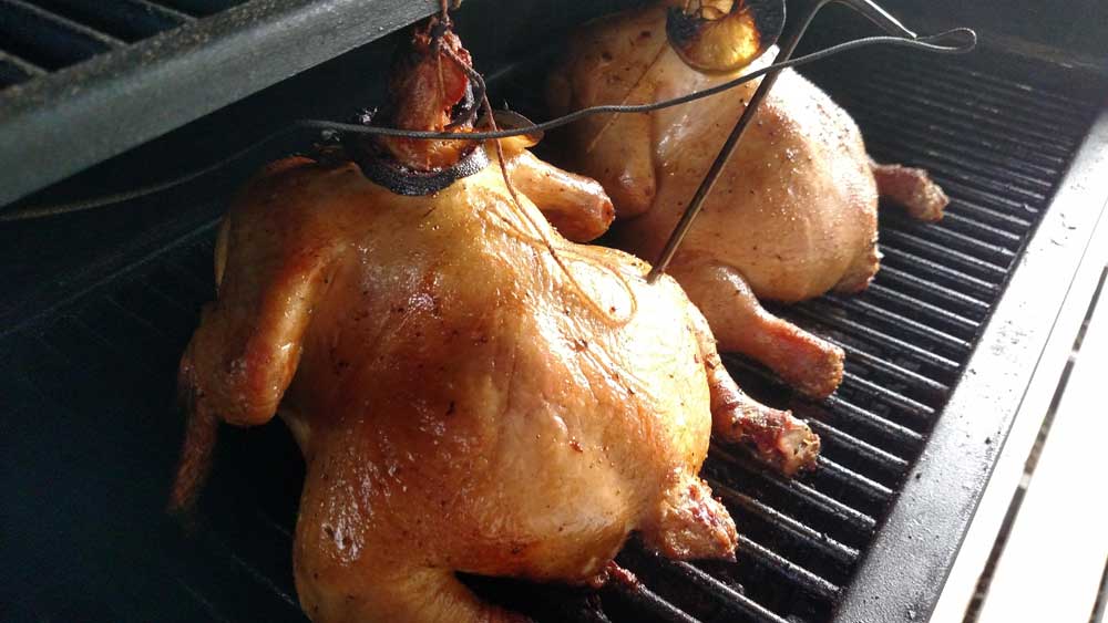 smoked chicken hanging on a pellet grill